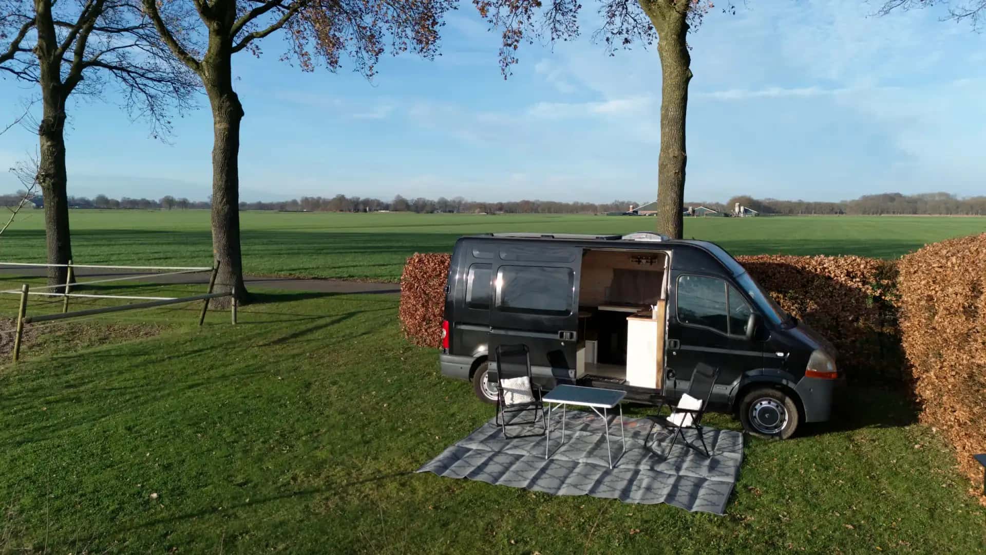 Camper op het erf van Woestenhoeve bij rustig avondlicht.